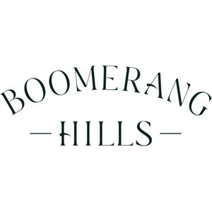 Boomerang Hills logo: The word BOOMERANG in dark green serif capitals curving in a wide arch above the word HILLS in the same capitals, with a short horizontal dash on either side of HILLS, on a plain white ground.