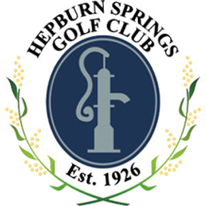 Hepburn Springs Golf Club logo: A navy oval enclosing a grey cast-iron mineral spring hand pump with Est. 1926 in white beneath it, under HEPBURN SPRINGS GOLF CLUB arched in black serif capitals, flanked by two green sprigs of pale yellow wattle blossom whose stems cross below.