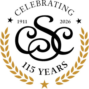 Salina Country Club logo: A black interlocking SC script monogram framed by two gold laurel branches, with CELEBRATING arched above between the dates 1911 and 2026 and two black stars, 115 YEARS curved below, and a gold star at the foot.