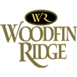 Woodfin Ridge Golf Club logo: A gold interlocked "WR" monogram inside a solid black horizontal oval, above two stacked lines of olive-gold serif capitals outlined in black reading "WOODFIN" and "RIDGE". No year.