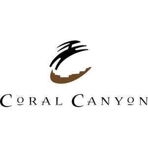 Coral Canyon Golf Course logo: A stylized long-muzzled animal head in profile facing left -- a deer or antelope with a single slit eye and two long horns swept back to the right -- drawn in tapering black brushstrokes above a brown crescent whose upper edge is notched into a stepped canyon-rim silhouette, with CORAL CANYON in letterspaced black serif capitals beneath.
