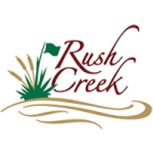 Rush Creek Golf Club logo: 'Rush Creek' in dark maroon script beside a green pennant flag rising from a clump of green marsh grass and tan cattails, all above a flowing gold swoosh standing for the creek.