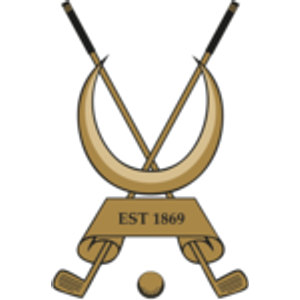 Alnmouth Golf Club logo: Two crossed tan golf clubs with black grips set behind a large tan upward-facing crescent, above a tan trapezoid banner reading 'EST 1869' in dark lettering, with a small tan golf ball below between the club heads.